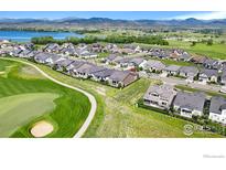 Stunning aerial view of homes near golf course and lake with beautiful mountain views in the background at 3304 Heron Lakes Pkwy, Berthoud, CO 80513