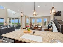 Bright eat-in kitchen features granite counters, stainless appliances, and seamless flow to the dining and living areas at 3304 Heron Lakes Pkwy, Berthoud, CO 80513