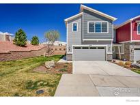 Two story home featuring gray horizontal siding, a gray garage door, and landscaped front yard at 4027 E 98Th Pl, Thornton, CO 80229