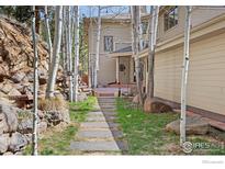A serene backyard featuring a stepping stone pathway amidst birch trees and rock outcroppings at 524 Cutter Ln, Boulder, CO 80302