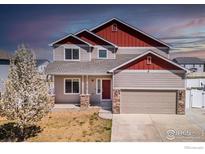 Charming two-story home featuring a red and beige exterior with an attached two-car garage and nicely landscaped front yard at 6709 2Nd St, Frederick, CO 80530