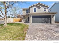 Charming two-story home with a gray exterior, attached garage, and a well-maintained lawn and landscaping at 10703 Butte Dr, Longmont, CO 80504