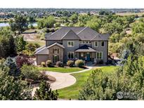 Beautiful two-story home featuring a well-manicured lawn, stone accents, and a welcoming entrance surrounded by lush greenery at 12648 Waterside Ln, Longmont, CO 80504