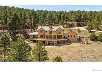 Expansive wooden home featuring a large deck and surrounded by mature trees at 1472 Timber Ln, Boulder, CO 80304