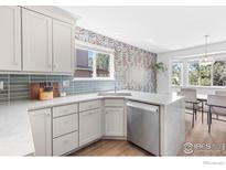 Well-lit kitchen with white cabinets, quartz countertops, and stainless steel appliances and view to dining nook at 1485 Stoneham St, Superior, CO 80027