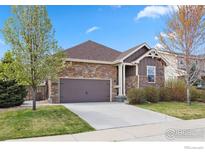 Beautiful one-story home with a stone facade, attached garage, and a well-manicured lawn at 1511 Bowen St, Longmont, CO 80501