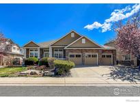 Inviting exterior showcasing a three-car garage, well-manicured landscaping, and stone accents at 1568 Stardance Cir, Longmont, CO 80504