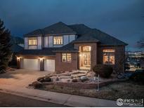 Stunning brick two-story home with a three-car garage, lush landscaping, and inviting entryway at 16261 W Ellsworth Ave, Golden, CO 80401