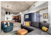 Open living area with modern decor, concrete ceiling, wood floors, and a glimpse of the kitchen at 1700 Bassett St # 409, Denver, CO 80202