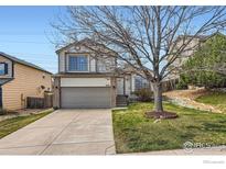 Two-story home featuring a two-car garage, brick accents, and a well-maintained front lawn at 21656 Hill Gail Way, Parker, CO 80138