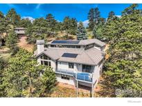 Stunning mountain home featuring a balcony, gray siding, and mature trees surrounding the property at 36 High View Dr, Boulder, CO 80304