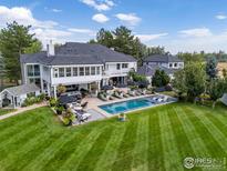 Expansive backyard with pool, manicured lawn, patio with furniture, and lush landscaping create an outdoor oasis at 5800 Saint Vrain Rd, Longmont, CO 80503