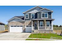 Beautiful two-story home showcasing a stone facade, covered porch, and well-manicured lawn at 1102 Ridgefield Dr, Berthoud, CO 80513