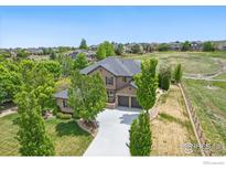 Stunning two-story home featuring a three-car garage, lush landscaping, and a view of open space at 14958 Wistera Way, Broomfield, CO 80023