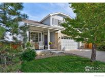 Charming two-story home featuring a brick facade, inviting porch, and well-maintained lawn and landscaping at 2279 Apple Tree Pl, Erie, CO 80516