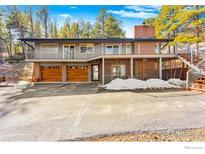 Modern two-story home with wood garage doors, gray siding and red brick exterior at 74 Sky Trail Rd, Boulder, CO 80302