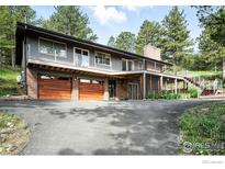 Two-story home featuring a multi-car garage, modern railing, and inviting curb appeal amidst mature trees at 74 Sky Trail Rd, Boulder, CO 80302