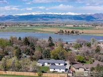 Stunning lakefront property with breathtaking mountain views, lush trees, and a charming home nestled in a serene landscape at 8138 Captains Ln, Longmont, CO 80504