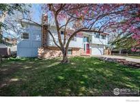 Charming two-story home with a red front door, brick facade, and blossoming tree in the front yard at 910 Sparta Dr, Lafayette, CO 80026