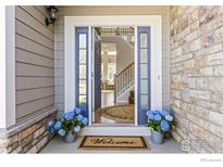 Inviting entryway featuring blue doors, a 'Welcome' mat, and a glimpse of the staircase and hardwood floors at 11722 Elmer Linn Dr, Longmont, CO 80504
