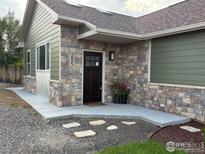 Charming home featuring stone accents, a dark-colored front door, and landscaped entrance at 205 S County Road 23, Berthoud, CO 80513