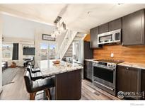 Modern kitchen features stainless steel appliances, island with granite countertops, and wood backsplash at 2201 Pearl St # 321, Boulder, CO 80302