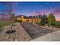 Stunning home with manicured landscaping, a circular driveway, and three-car garage, set against a beautiful sunset sky at 3796 Vale View Ln, Mead, CO 80542