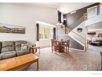 Open-concept living room with high ceilings, large windows, and a staircase to the second floor at 4170 Combine Pl, Brighton, CO 80601