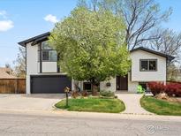 Charming two-story home featuring a well-manicured lawn and a beautiful flowering tree at 6672 Welch Ct, Arvada, CO 80004