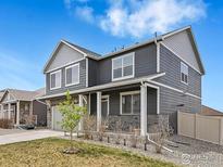 Charming two-story home with gray siding, stone accents, and a manicured front yard at 7231 Clarke Dr, Frederick, CO 80530