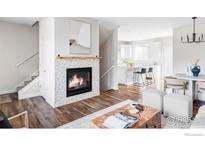 Bright, open-concept living area with fireplace, hardwood floors and access to dining and kitchen at 11488 E 25Th Dr, Aurora, CO 80010