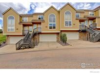 Townhome exterior featuring a two-car garage, a stairway leading to the front door, and a tan facade at 1757 High Plains Ct, Superior, CO 80027