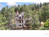 Tudor-style home with a mix of timber framing and stucco, surrounded by mature trees at 24771 Westridge Rd, Golden, CO 80403