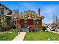 Charming brick home featuring a cozy front porch and well-maintained lawn at 3059 N York St, Denver, CO 80205