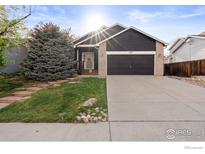 Charming front exterior with a well-maintained lawn, attractive landscaping, and a two-car garage at 1181 Dover Way, Broomfield, CO 80020