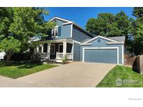 Charming two-story home featuring a covered porch, attached garage, and well-maintained lawn at 1696 Bain Dr, Erie, CO 80516