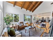 Bright living room boasts vaulted ceilings with wood beams, large windows with mountain views, and hardwood floors at 251 Ridgeview Ln, Boulder, CO 80302
