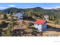 Mountain home with a red roofed detached garage, stairs, and lush trees against a serene mountain backdrop at 319 Camino Bosque, Boulder, CO 80302