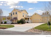 Two-story yellow home with a wide driveway and a well-manicured lawn at 3530 Willow Rd, Frederick, CO 80504