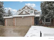 Charming two-story home featuring a brick facade and a three-car garage, set against a snowy landscape at 520 Campo Way, Superior, CO 80027