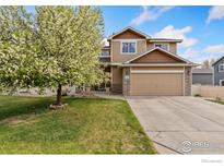 Charming two-story home featuring a well-manicured lawn and blooming tree at 5452 Rustic Ave, Firestone, CO 80504
