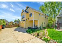 Charming two-story yellow home with a front porch, attached garage, and well-maintained landscaping at 740 Boxwood Ln, Longmont, CO 80503