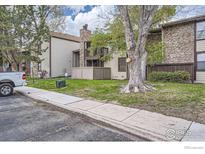 Exterior view of a home with neutral siding, stone accents, and a well-maintained front lawn at 7720 W 87Th Dr # N, Arvada, CO 80005