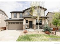 Charming two-story home featuring a well-manicured lawn, covered porch, and a two-car garage at 8346 Wilkerson Ct, Arvada, CO 80007