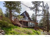 Charming exterior of a gray home with a wooden deck and mature trees at 93 Pine Needle Rd, Boulder, CO 80304
