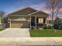 Charming single-story home with a two-car garage, a manicured lawn, and stone accents under a lovely pink and blue sky at 11166 Charles St, Firestone, CO 80504