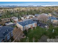 Wide aerial view of building exteriors, grass area, and mountain backdrop at 1608 Cottonwood Dr # 6, Louisville, CO 80027