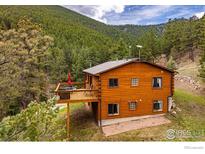 Exterior of a log cabin-style home with a deck, nestled in a forest setting at 310 Wendelyn Way, Boulder, CO 80302