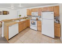 Charming kitchen with wood cabinets, white appliances, and a breakfast bar overlooking the living area at 5425 County Road 32 # 15, Mead, CO 80504