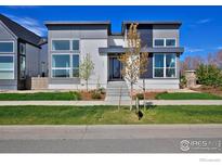 Modern home with gray and white exterior, large windows, and professionally landscaped front yard at 603 Mountain Dr, Longmont, CO 80503